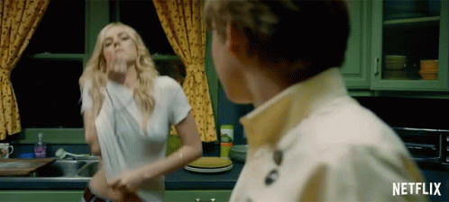 A Woman In A White Shirt Is Dancing In A Kitchen With A Netflix Logo GIF