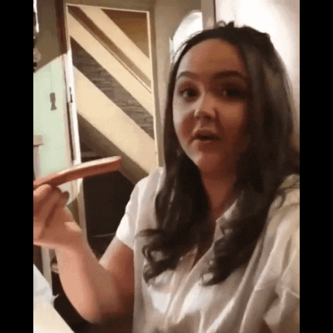 A Woman In A White Shirt Is Holding A Sausage In Her Hand GIF