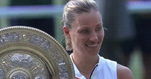 a woman in a white shirt is holding a trophy
