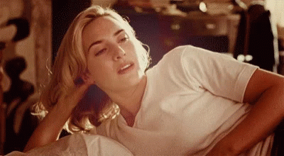 A Woman In A White Shirt Is Laying Down With Her Head On Her Hand GIF