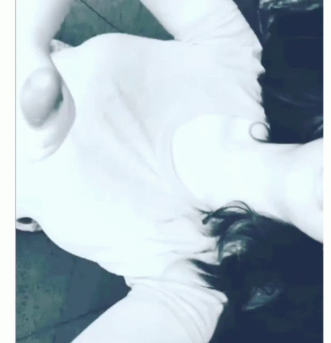 A Woman In A White Shirt Is Laying On Her Back GIF
