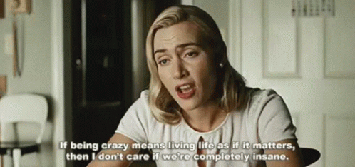 A Woman In A White Shirt Is Sitting At A Table With A Quote On It . GIF