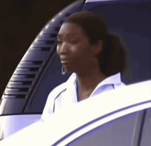 A Woman In A White Shirt Is Sitting In A Car GIF