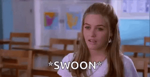 A Woman In A White Shirt Is Sitting In A Classroom And Making A Funny Face . GIF