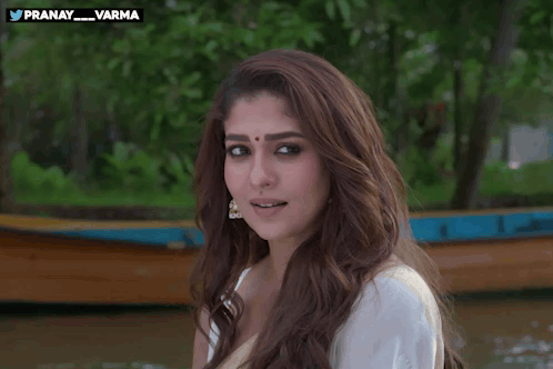 a woman in a white shirt is smiling and waving in front of a boat with the hashtag pranay_varma