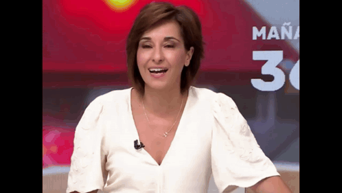 a woman in a white shirt is smiling in front of a sign that says mañana