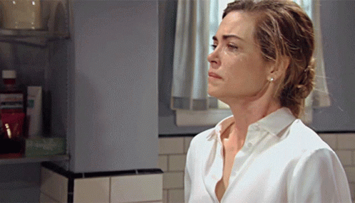 A Woman In A White Shirt Is Standing In A Bathroom Looking Down GIF