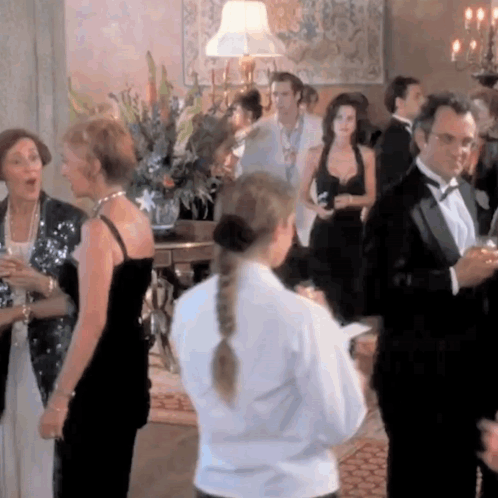 A Woman In A White Shirt Is Standing In A Crowd GIF
