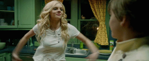 A Woman In A White Shirt Is Standing In A Kitchen With Her Arms Outstretched GIF