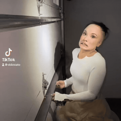 A Woman In A White Shirt Is Standing In Front Of A Wall With A Tiktok Watermark GIF
