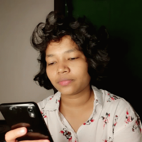 A Woman In A White Shirt Looks At Her Redmi Phone GIF
