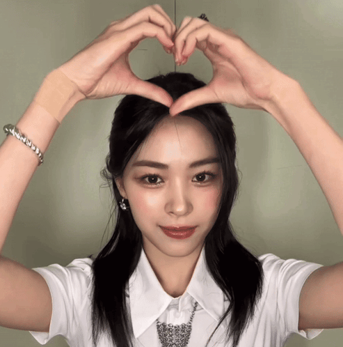 A Woman In A White Shirt Making A Heart With Her Hands GIF