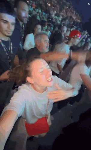 A Woman In A White Shirt With A Red Purse Is Dancing In A Crowd GIF