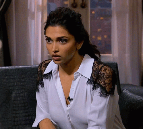 A Woman In A White Shirt With Black Lace Sleeves Looks Surprised GIF
