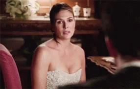 A Woman In A White Strapless Dress Is Sitting Next To A Man In A Suit . GIF