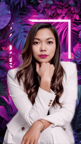 A Woman In A White Suit Is Sitting In Front Of Purple Leaves GIF