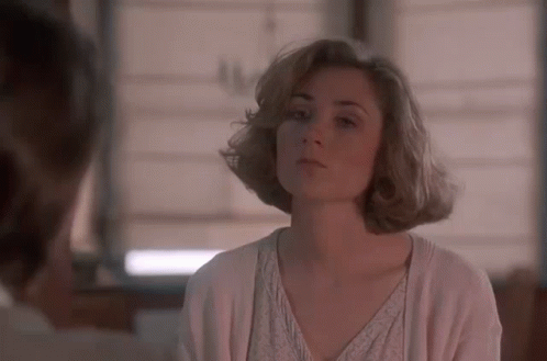 A Woman In A White Sweater Is Looking At A Man In A Room . GIF