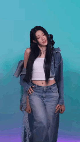A Woman In A White Tank Top And Jeans Is Standing In Front Of A Blue And Purple Background . GIF