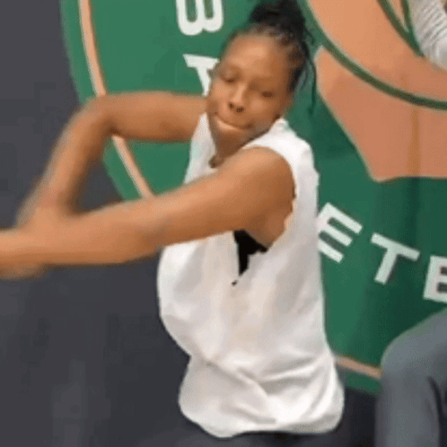A Woman In A White Tank Top Is Dancing In Front Of A Sign That Says Boston GIF