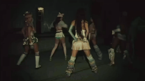 A Woman In A White Top And Blue Gloves Is Dancing In Front Of Two Other Women . GIF