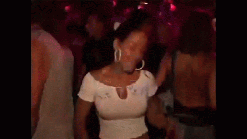 a woman in a white top is dancing in a crowd