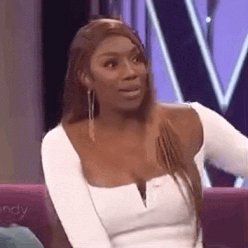 A Woman In A White Top Is Sitting On A Couch . GIF