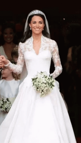 A Woman In A White Wedding Dress Is Holding A Bouquet Of White Flowers . GIF
