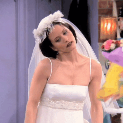 A Woman In A White Wedding Dress With A Veil GIF