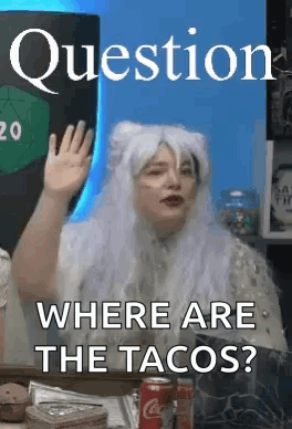 A Woman In A White Wig Is Sitting At A Table Waving Her Hand . GIF