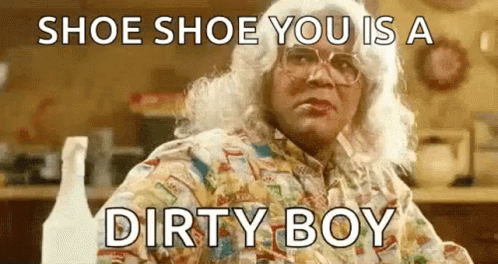A Woman In A Wig And Glasses Is Sitting At A Table With A Bottle Of Spray . GIF
