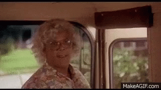 A Woman In A Wig And Glasses Is Standing In A Bus . GIF