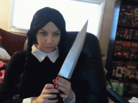 a woman in a wig holds a large knife in her hands
