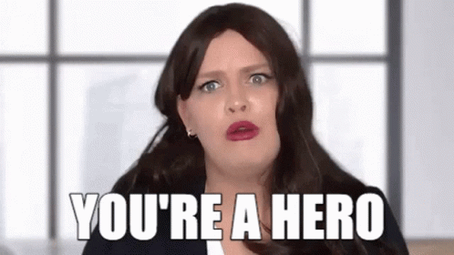 A Woman In A Wig Is Saying `` You 'Re A Hero '' While Making A Funny Face . GIF
