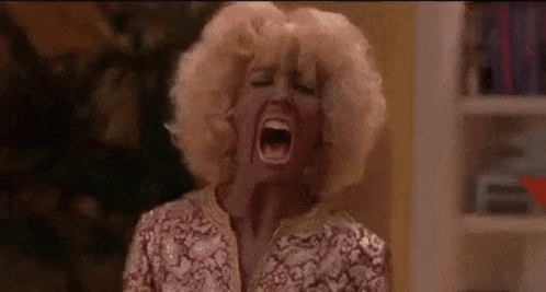 A Woman In A Wig Is Screaming With Her Mouth Open . GIF