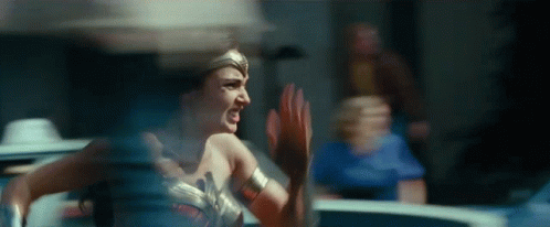A Woman In A Wonder Woman Costume Is Running And Screaming In A Room . GIF