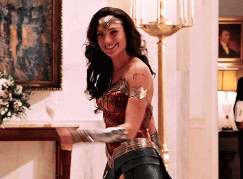 A Woman In A Wonder Woman Costume Is Standing In A Room . GIF
