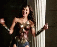 A Woman In A Wonder Woman Costume Is Standing In Front Of A Pillar . GIF
