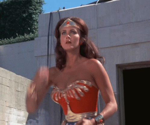 A Woman In A Wonder Woman Costume Is Waving GIF