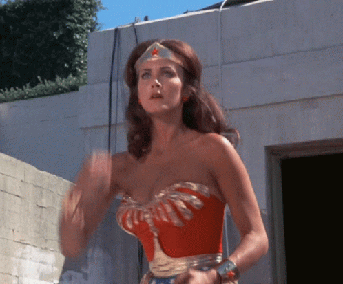 A Woman In A Wonder Woman Costume Is Waving GIF