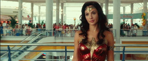 A Woman In A Wonder Woman Costume Stands In A Crowded Mall GIF