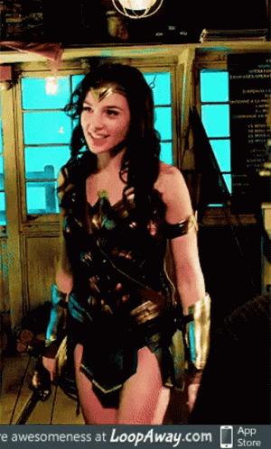 A Woman In A Wonder Woman Costume Stands In Front Of A Window GIF
