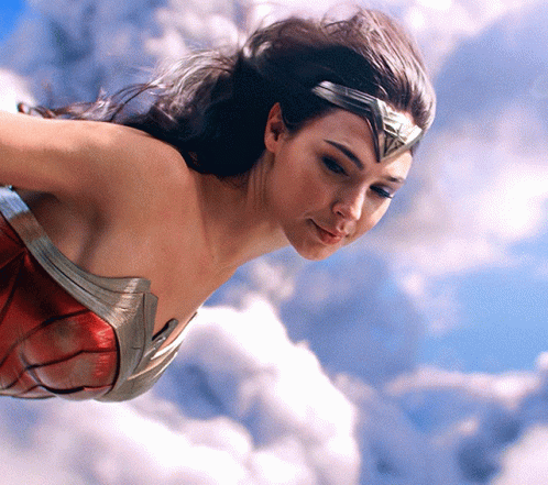 A Woman In A Wonder Woman Outfit Is Flying Through The Air GIF