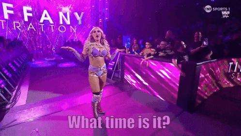 A Woman In A Wrestling Outfit Is Standing In Front Of A Crowd And Says What Time Is It .. GIF