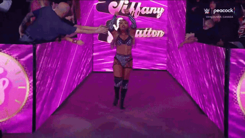 A Woman In A Wrestling Outfit Is Walking Through A Purple Tunnel GIF