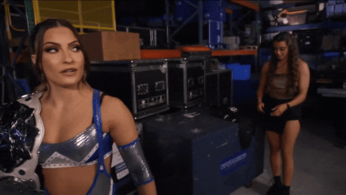 a woman in a wrestling outfit stands in front of a blue box that says ' warehouse ' on it