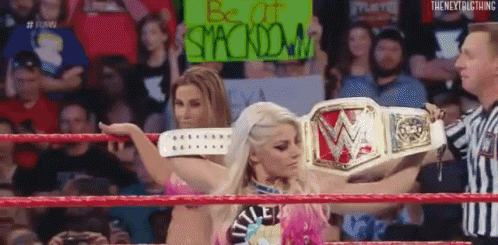 A Woman In A Wrestling Ring Holding A Sign That Says Be At Stackdown . GIF