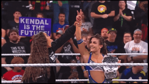 a woman in a wrestling ring holds a sign that says kendal is the future