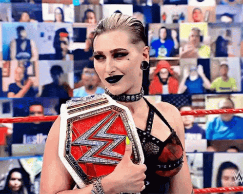 A Woman In A Wrestling Ring Is Holding A Championship Belt . GIF