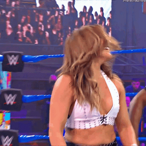 A Woman In A Wrestling Ring Is Wearing A White Top With A W Logo On It GIF