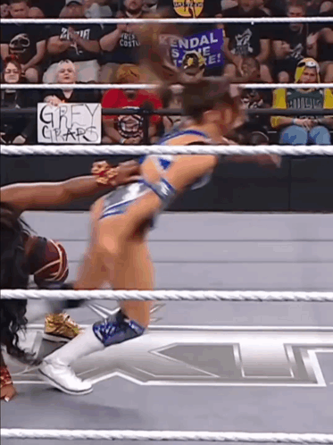a woman in a wrestling ring with a sign behind her that says grey claw